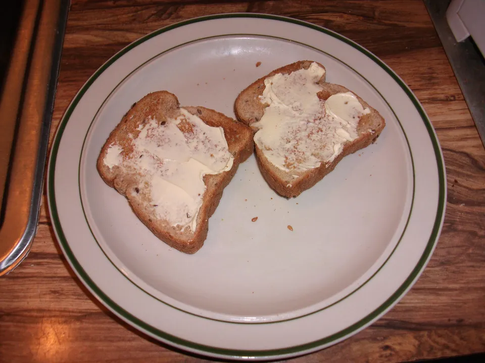 Dos rebanadas de pan tostado con mantequilla derretida sobre un plato blanco